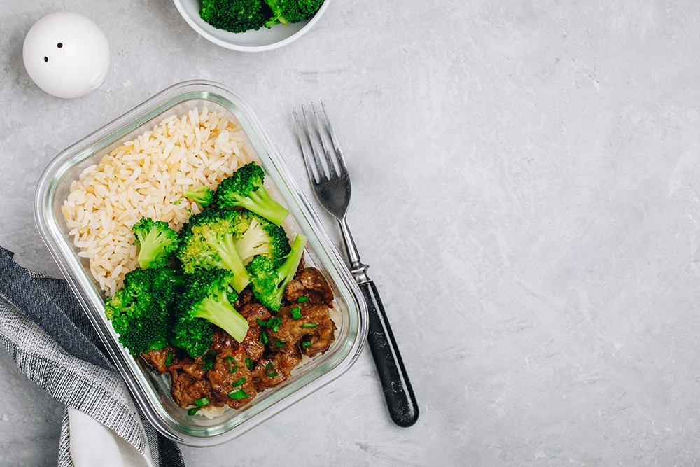 Glasbehälter mit vorgekochter Mahlzeit bestehend aus Fleisch mit Reis und Brokkoli