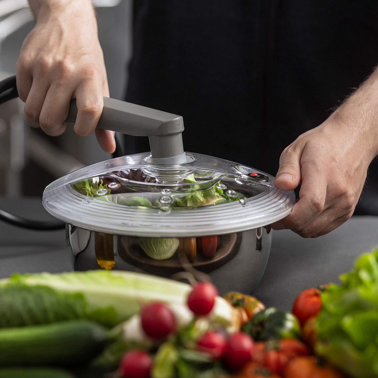 Stainless steel container filled with green salad is vacuumed using a suction device