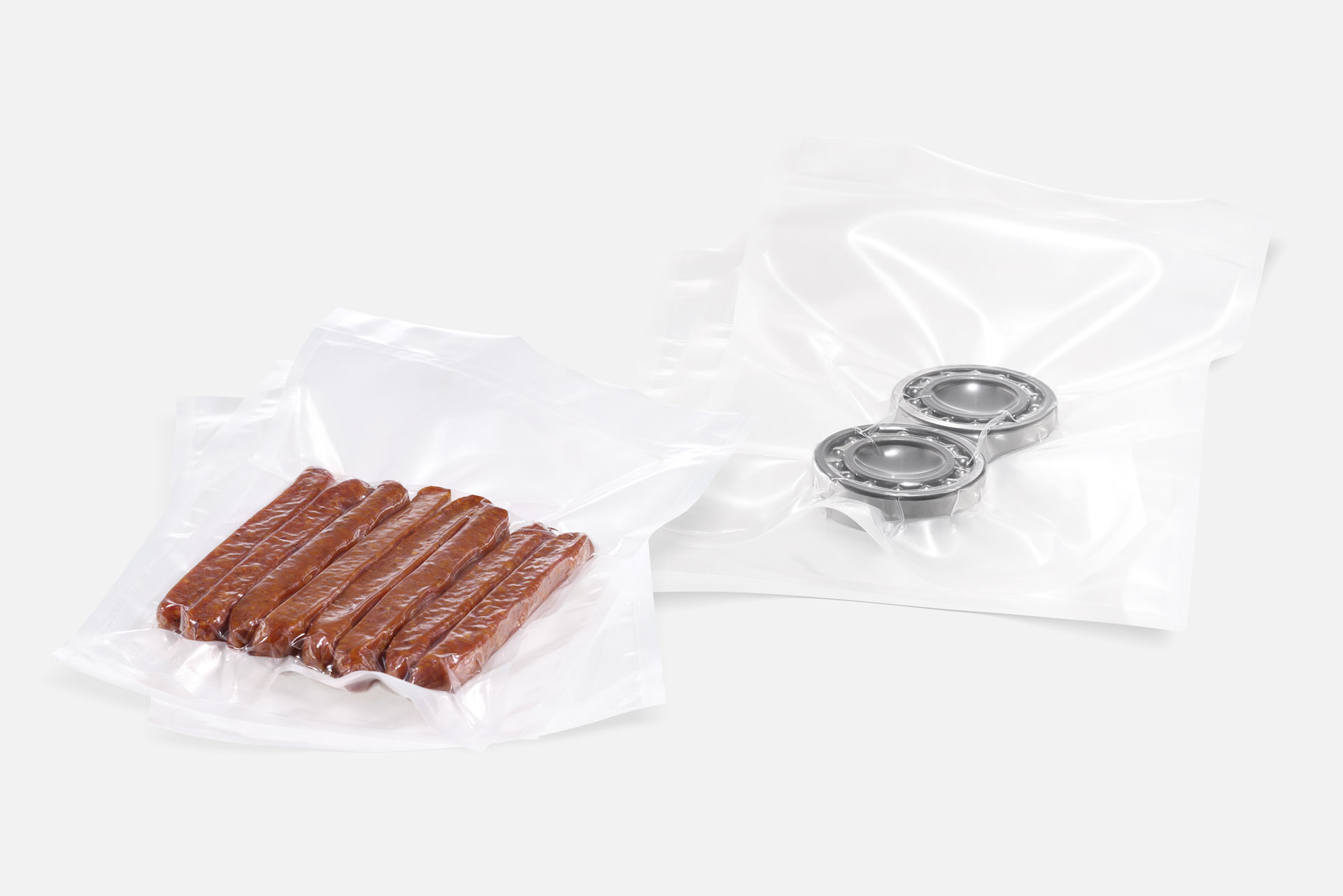 Two structured transparent vacuum bags vacuum-sealed with food and industrial parts