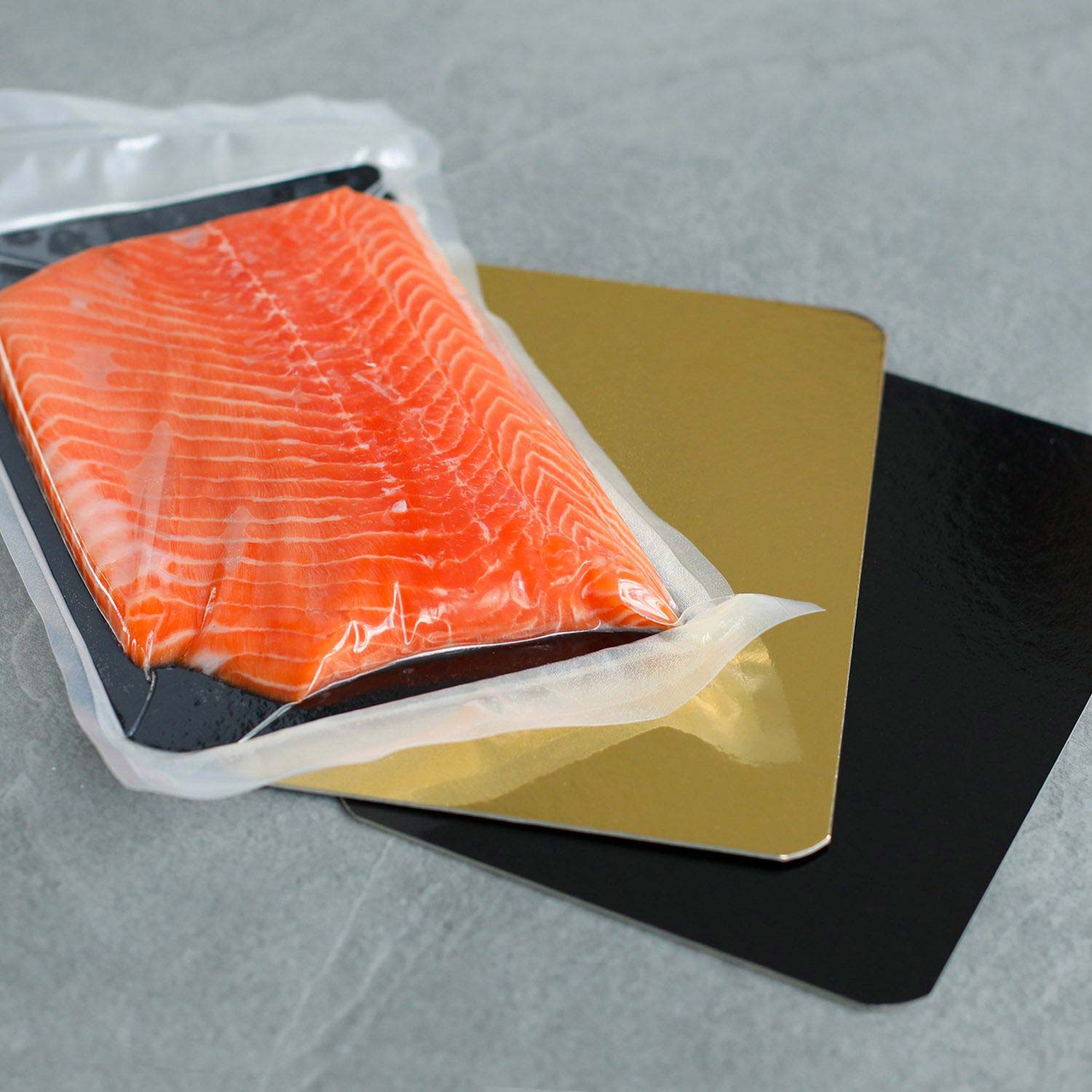 Salmon boards with golden and black side, along with vacuum-sealed salmon fillet