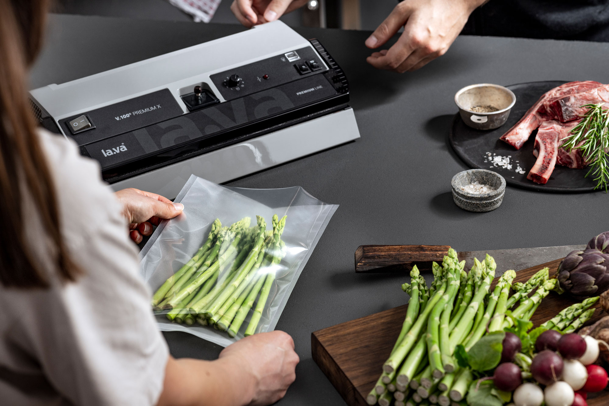 Green asparagus is in a vacuum bag in front of a Lava vacuum sealer