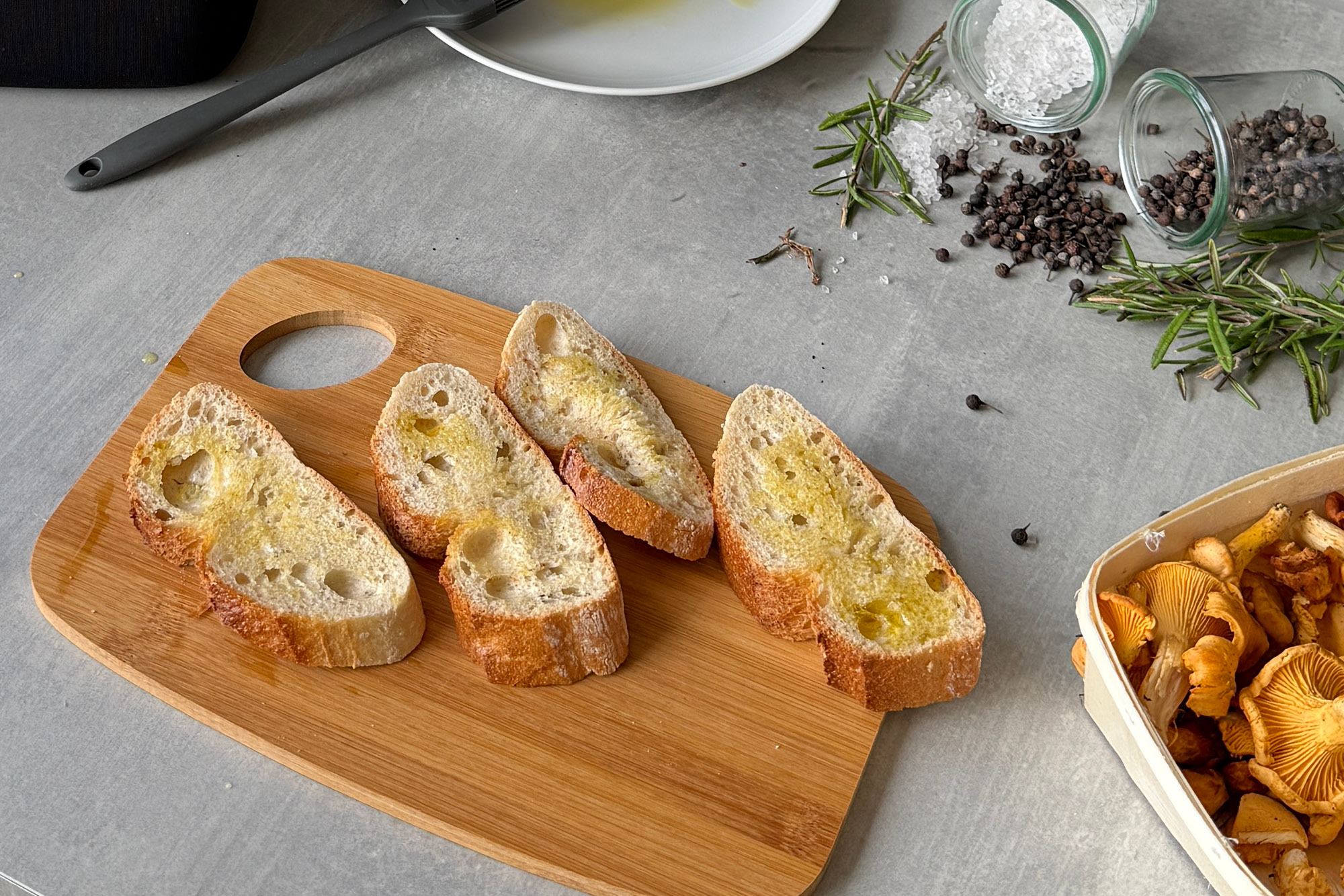 Geröstetes Brot mit Olivenöl und Kräutern vorbereiten. Vier Ciabatta-Scheiben mit Olivenöl, Kräutern, Pfeffer und Meersalz auf Brett