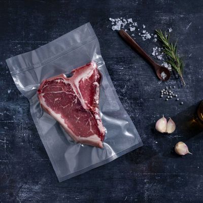 Transparenter strukturierter Vakuumbeutel mit T-Bone Steak vakuumversiegelt